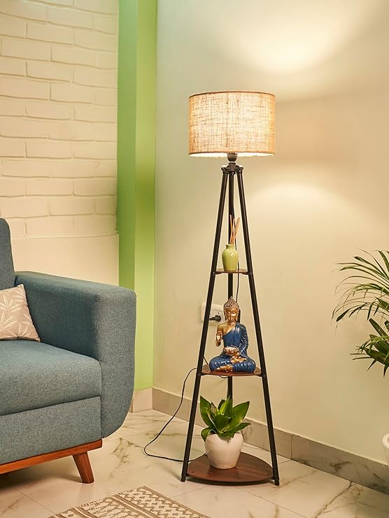 Modern metal floor lamp with fabric shade, featuring shelves holding a Buddha statue