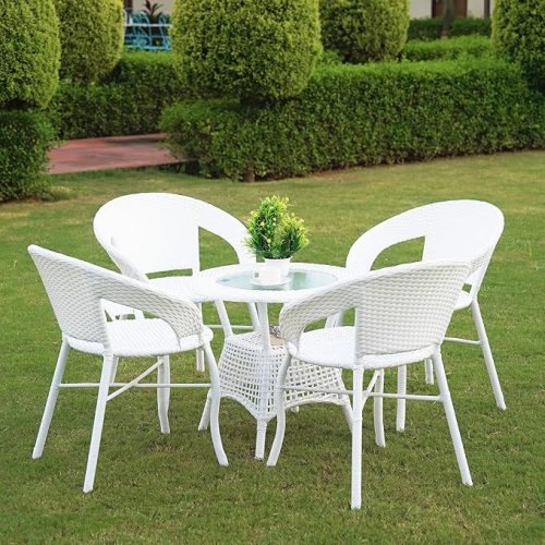 Elegant white rattan garden furniture set with four chairs and a glass-top table placed on a green lawn, perfect for outdoor dining and relaxation.