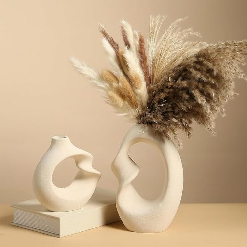 Set of two beige ceramic decorative donut vases with abstract hollow design, styled with pampas grass for modern home décor.