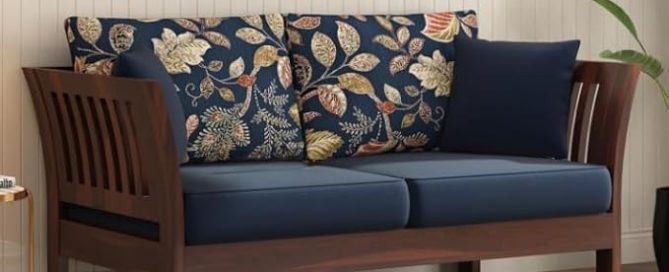 A two seater couch with a dark wood frame and navy blue cushions. The back pillows have a decorative floral pattern.